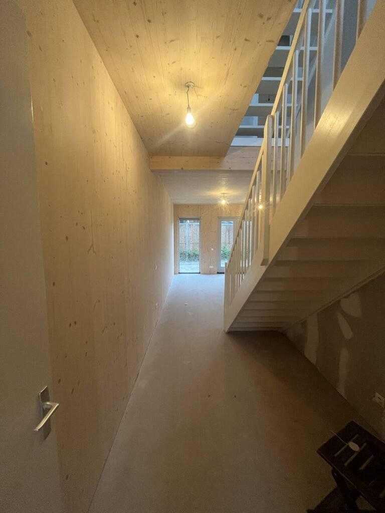 CLT interieur met beschermde houten wanden en plafonds, plus wit gespoten trap en balustrade voor een moderne, lichte woonkwaliteit – uitgevoerd door LenKraft, Twente