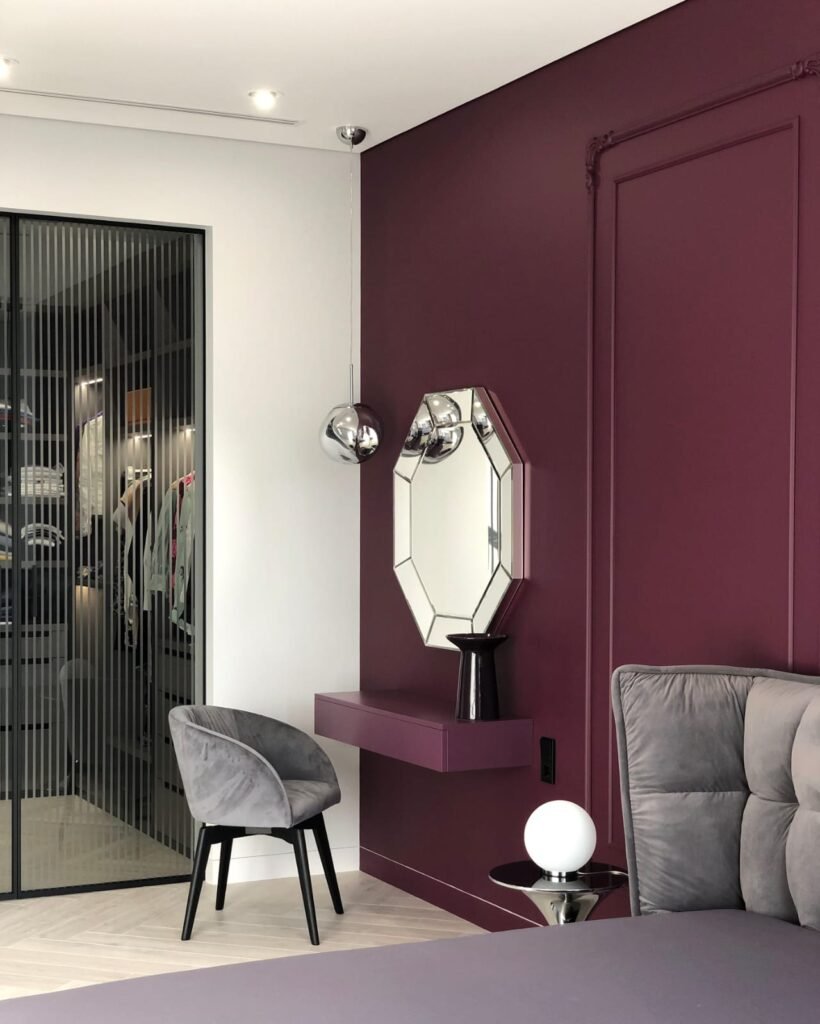Diep matte aubergine wand met klassiek lijstwerk en zwevende console, strak gespoten door LenKraft Design – luxe slaapkamer in Twente